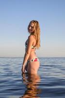 blond fille dans une bikini permanent dans le mer l'eau. magnifique youn photo