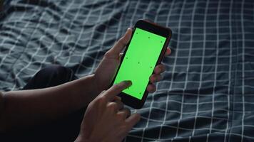 deux mains en portant une téléphone intelligent avec une vert écran maquette cadre, avec les doigts montrer du doigt à le écran photo