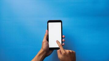 main de homme en portant mobile téléphone intelligent et montrer du doigt avec doigt à écran sur bleu Contexte photo