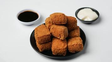 frit Tofu sur une noir assiette avec Mayonnaise et sucré soja sauce sur une blanc Contexte photo