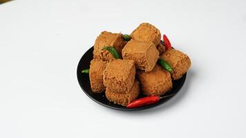 frit Tofu sur une noir assiette avec piments dans une blanc Contexte photo