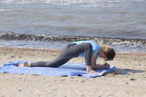 fille les pratiques yoga par le mer. exercice gymnastique dans le Frais air par le mer. photo