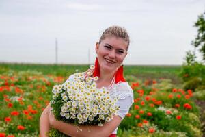 Jeune fille avec une bouquet de marguerites dans champ. marguerites sur une coquelicot champ. photo