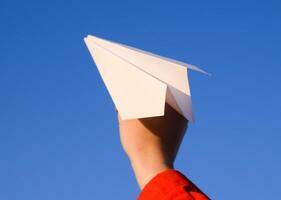 blanc papier avion dans main contre le ciel. une symbole de liberté sur le l'Internet photo