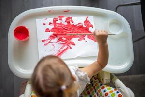 mignonne peu fille La peinture avec brosses à maison. Créatif Jeux pour enfants. rester à Accueil divertissement photo