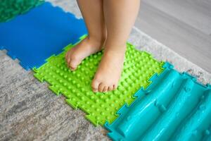 proche en haut vue de peu fille des promenades sur une massage tapis. bambin bébé pied massage tapis. des exercices pour jambes orthopédique massage tapis. photo