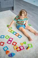 peu fille en jouant coloré aimant Plastique blocs trousse à maison. le enfant en jouant éducatif Jeux. de bonne heure enfance développement. photo