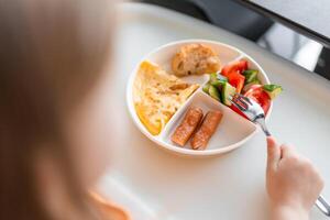 peu fille avoir une équilibré petit déjeuner dans Accueil cuisine dans le Matin photo