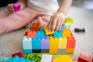 peu fille jouer avec constructeur jouet sur sol dans maison, éducatif jeu, dépenses loisir Activités temps concept photo