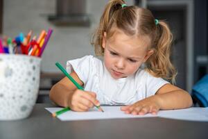 peu fille dessine avec coloré des crayons dans maison. photo