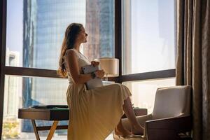 élégant femme d'affaires pigiste avec portable séance sur table et profiter panoramique vue dans le ville Contexte. faible clé photo. haute qualité photo