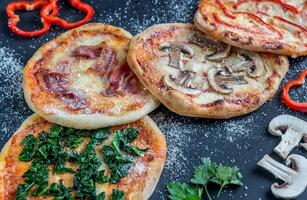 mini-pizzas avec diverses garnitures sur la planche de bois photo