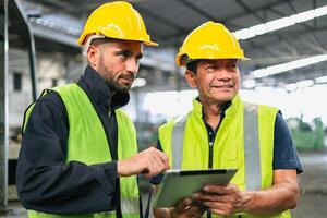 deux ingénieur Regardez projets et Planification avec tablette mobile dans usine photo