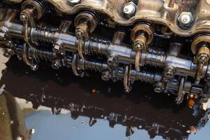 le tête de le bloquer de cylindres. le tête de le bloquer de cylindres supprimé de le moteur pour réparation. les pièces dans moteur huile. voiture moteur réparation dans le un service photo