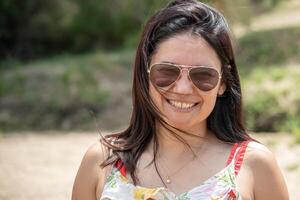 portrait de une hispanique touristique femme portant des lunettes et coloré robe. photo