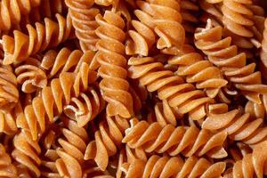 non cuit entier grain fusilli Pâtes. une culinaire Toile de entier blé spirales, création une animé et texturé Contexte pour gourmet cuisson. entier grain tordu sec Pâtes. entier blé brut macaroni photo