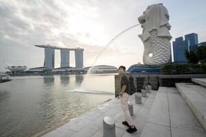 homme dans merlion Fontaine dans de face de le Marina baie photo