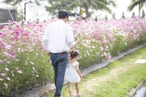 peu fille avec sa père sur la nature Contexte une retour vue de le père dans paradis concept. père détient fille main comme elle des promenades. photo