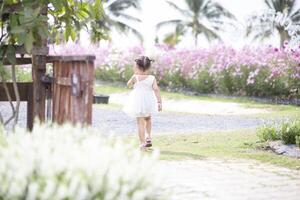 une content Jeune fille admire et doucement touche et admire une épanouissement fleur. il reflète le beauté de printemps et le Facile joies de étant dans contact avec la nature. photo