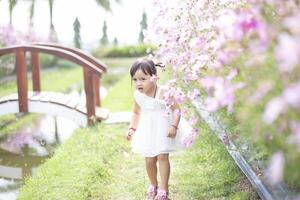 une content Jeune fille admire et doucement touche et admire une épanouissement fleur. il reflète le beauté de printemps et le Facile les plaisirs de étant dans contact avec la nature. printemps éveil. photo