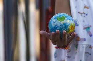 les filles mains avec une globe avec une Contexte de solaire panneaux concept de économie le monde avec renouvelable énergie. photo