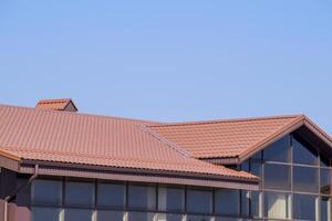 une bâtiment avec une rouge-marron toit. moderne matériaux de terminer et toiture photo