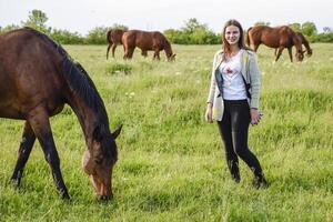 le fille est caressant le cheval. fille avec les chevaux dans le pâturage. photo