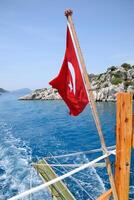 dinde drapeau à le arrière de une plaisir yacht. vue de méditerranéen côte photo
