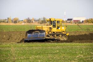 le Jaune tracteur avec attaché grédérom fait du sol mise à niveau. photo