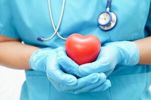 femme médecin asiatique tenant un coeur rouge pour la santé à l'hôpital. photo