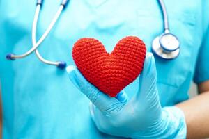 femme médecin asiatique tenant un coeur rouge pour la santé à l'hôpital. photo