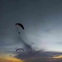 silhouette de une parapente planant dans le après midi ciel. extrême des sports. photo