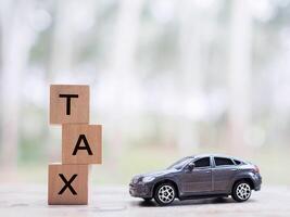 jouet voiture et en bois blocs avec le mot impôt . le concept pour payant impôt pour voiture dans futur photo