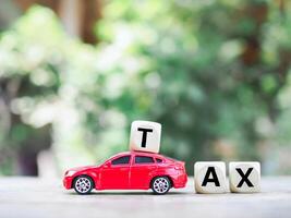 jouet voiture et en bois blocs avec le mot impôt . le concept pour payant impôt pour voiture dans futur photo