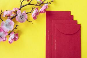 Haut vue de chinois Nouveau année rouge paquet et Cerise fleur décoration avec personnalisable espace pour texte ou vœux. chinois Nouveau année fête concept. photo