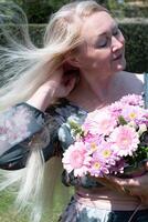 âge moyen femme avec une bouquet de rose Gerberas une cadeau pour de la mère jour, printemps photo