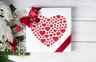 la Saint-Valentin journée cadeau, rouge cœur praliné boîte et fleur bouquet sur blanc table photo