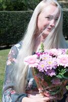 âge moyen femme avec une bouquet de rose Gerberas une cadeau pour de la mère jour, printemps photo