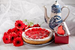 encore vie, une femme coupes une fraise tarte sur une table décoré avec rouge Gerberas photo