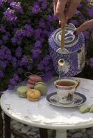 Extérieur pique-nique avec une tasse de à base de plantes thé et macaron Gâteaux, une femme main verse photo