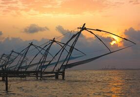 chinois filets de pêche sur le coucher du soleil. Kochi, Kerala, Inde photo