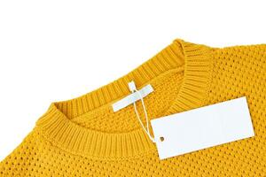 Étiquette de vêtements rectangulaire blanc blanc sur pull tricoté jaune isolé sur fond blanc photo