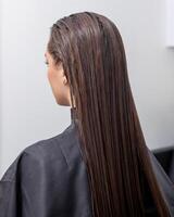 photo de une européen fille avec longue et magnifique brunette cheveux à le beauté salon. brillant et en bonne santé cheveux.