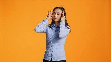 asiatique Jeune adulte souffre de douloureux migraine dans studio, frottement les temples à facilité les temples pression. malade inquiet femme sentiment en dessous de stress, transaction avec mal de crâne et tension. photo