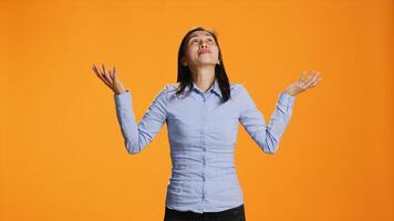 spirituel femme prier à Jésus dans de face de Orange arrière-plan, en présentant sa Reconnaissance à Dieu pendant prière session. asiatique la personne montrant croyance et Foi dans religion, demander pour paix. photo