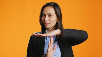 Jeune femme montrant temps libre symbole dans studio, demander pour une Pause après travail dur. asiatique la personne permanent plus de arrière-plan, en présentant pause geste avec mains, sur de soi modèle. photo