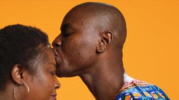 romantique homme embrasser front de le sien petite amie dans studio et exprimer honnête vrai l'amour pour son, sucré affection. soins mari montrant mignonne sincère émotions pour le sien épouse. proche en haut. photo