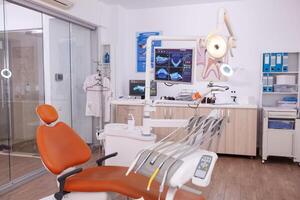 vide médical clinique orthodontique hôpital pièce avec stomatologie dentaire équipement, prêt pour dentisterie chirurgie. orthodontiste chaise avec personne sur il, les dents diagnostic radiographie images sur afficher photo