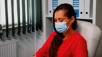 portrait de femme avec protection masque à la recherche et travail sur ordinateur. employé dans Nouveau Ordinaire Bureau espace de travail dactylographie sur ordinateur clavier à la recherche à bureau respectant social distanciation photo