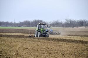 luxuriant et desserrer le sol sur le champ avant semis. le tracteur charrues une champ avec une charrue photo